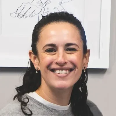 Dr. Alex Powers smiling at the camera while wearing a gray sweater